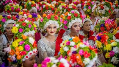 Indonesia kaya akan tradisi dan budaya yang diwariskan dari generasi ke generasi. Salah satu tradisi yang menarik dan masih dilestarikan hingga saat ini adalah adat Ngarot, sebuah upacara khas yang berasal dari masyarakat Kecamatan Lelea, Kabupaten Indramayu, Jawa Barat. Tradisi ini memiliki nilai historis dan kultural yang sangat berarti, terutama dalam konteks kehidupan pertanian masyarakat setempat. Sejarah dan Makna Adat Ngarot Adat Ngarot diyakini telah ada selama ratusan tahun. Istilah "Ngarot" berasal dari bahasa Sunda yang berarti "minum" atau "menyegarkan diri." Filosofi di balik tradisi ini berkaitan dengan kesejahteraan dan kesuburan dalam bertani, sehingga sering dilaksanakan menjelang musim tanam padi sebagai ungkapan rasa syukur kepada Tuhan atas tanah yang subur. Selain berfungsi sebagai ungkapan syukur, Ngarot juga menjadi kesempatan untuk bersilaturahmi dan memberikan penghormatan kepada para petani muda yang akan memulai masa tanam. Tradisi ini menanamkan nilai kebersamaan dan gotong royong dalam komunitas agraris Indramayu. Prosesi Upacara Ngarot Upacara Ngarot biasanya berlangsung setiap bulan November atau Desember, tergantung pada penanggalan pertanian. Pelaksanaan dipimpin oleh kuwu (kepala desa) setempat dan melibatkan pemuda-pemudi desa yang disebut panggalih (pemuda) dan manggarot (pemudi). • Persiapan o Pemuda dan pemudi yang ingin berpartisipasi harus memenuhi beberapa kriteria, seperti belum menikah dan memiliki perilaku baik di masyarakat. o Peserta perempuan mengenakan kebaya berwarna-warni serta mahkota bunga sebagai simbol kesucian dan kesuburan. o Peserta laki-laki mengenakan pakaian tradisional petani. • Prosesi Ngarot o Rombongan peserta berkumpul di balai desa. o Kuwu memberikan wejangan berupa nasihat hidup dan doa keselamatan. o Setelah wejangan, peserta menikmati hidangan khas bersama sebagai simbol kebersamaan dan rezeki yang melimpah. • Ritual Hiburan dan Kesenian o Setelah prosesi utama, upacara diakhiri dengan pertunjukan seni daerah, seperti tarian tradisional dan musik khas Indramayu. o Warga desa turut merayakan dengan berbagai hiburan dan pesta rakyat. Nilai Budaya dalam Ngarot Tradisi Ngarot memiliki banyak nilai budaya yang tetap relevan hingga kini, antara lain: • Gotong Royong: Mengajarkan pentingnya kerja sama dalam kehidupan sosial. • Kesetiaan pada Tradisi: Memperkuat identitas budaya masyarakat agraris Indramayu. • Kesucian dan Kesopanan: Peserta diharapkan memiliki perilaku baik sebagai simbol kemurnian hati. Pelestarian Adat Ngarot Di era modern ini, adat Ngarot tetap dijaga dan dilestarikan oleh masyarakat Indramayu sebagai warisan budaya. Pemerintah daerah juga mendukung tradisi ini dengan memasukkannya ke dalam agenda wisata budaya tahunan, sehingga lebih banyak orang dapat mengenal dan menghargai kekayaan tradisi lokal. Adat Ngarot bukan hanya sekadar ritual, tetapi juga merupakan bentuk penghormatan terhadap alam dan warisan nenek moyang. Dengan terus menjalankan tradisi ini, masyarakat Indramayu menunjukkan bahwa budaya dan identitas lokal tetap memiliki tempat yang penting di tengah arus globalisasi.